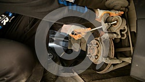 Auto mechanic working on brakes in a car repair shop domestic garage.