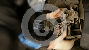 Auto mechanic working on brakes in a car repair shop domestic garage.