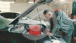 Auto mechanic working on car diagnostic in a repair shop. Electrician working on car engine. Mechanic repairs car in a