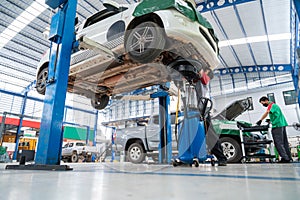 Auto mechanic working in Car repair station paved with epoxy floor and electric lift for a car that comes to change the engine oil