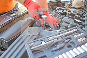 Auto mechanic working in garage during the maintenance of engine. Mechanician holding wrench tool during Repair of a car