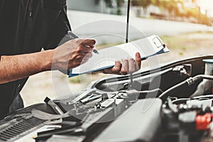 Auto mechanic working in garage Technician holding clipboard and check mechanic Maintenance car check