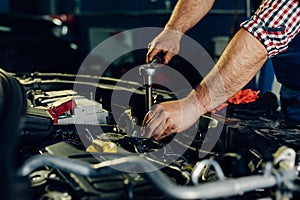 Auto mechanic working on car engine in mechanics garage