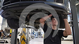 An auto mechanic working under the car on a car lift in the garage. Car service.