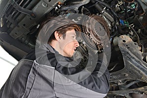 Auto mechanic working under the car and changing clutch