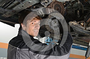 Auto mechanic working under the car and changing clutch photo