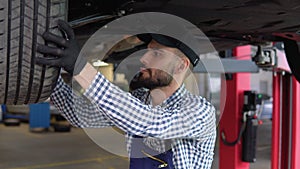 Auto mechanic working under car on hydraulic lift in garage