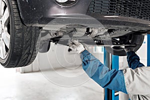 Auto mechanic working under car on a lift. oil change