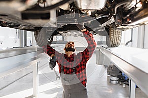 Auto mechanic working underneath a lifted car. Auto mechanic working in garage. Repair service