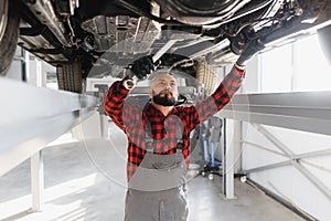 Auto mechanic working underneath a lifted car. Auto mechanic working in garage. Repair service