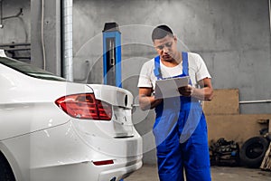 Auto mechanic writes inspection results on clipboard