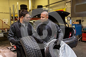 Auto mechanics changing car tires at workshop