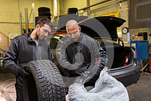 Auto mechanics changing car tires at workshop