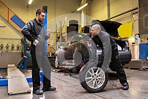 Auto mechanics changing car tires at workshop