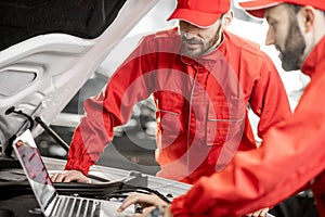 Auto mechanics doing diagnostics with laptop