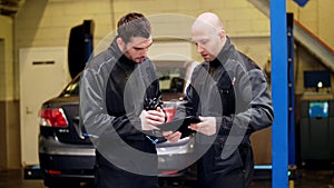 Auto mechanics with tablet pc talking at car shop