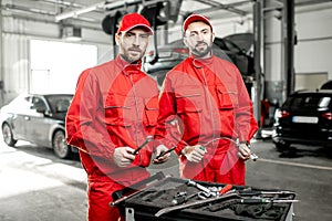 Auto mechanics with wrenches at the car service