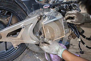 Auto motorcycle radiator Being disassembled by the hands of a motorbike mechanic Hands wearing gloves. So soiled cloth