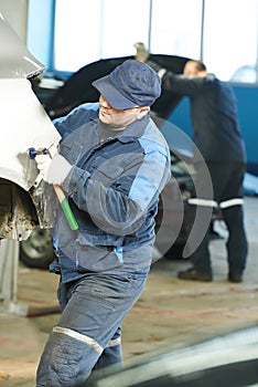 Auto repair man flatten metal body car photo