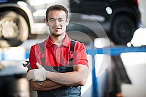 Auto repair service. Handsome smiling mechanic with car