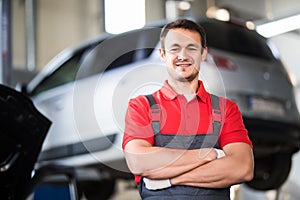 Auto repair service. Handsome smiling mechanic with car