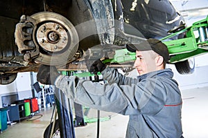 Auto repair service. Mechanic works with car suspension