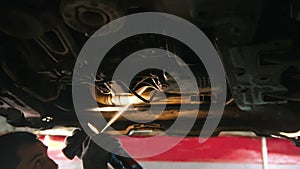 Auto repair shop - man working under the car - spraying an anti-oxidation disinfectant under the car