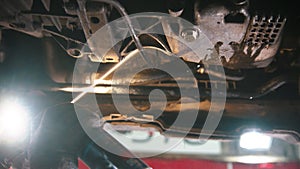 Auto repair shop - man working under the car - spraying an anti-oxidation disinfectant under the car and removing rust