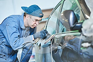 Auto repairman grinding autobody bonnet