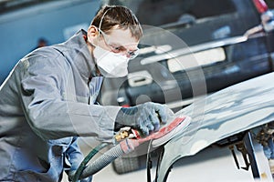 Auto repairman grinding autobody bonnet