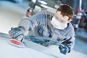 Auto repairman grinding autobody bonnet