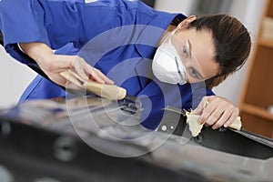 Auto repairman grinding autobody bonnet photo