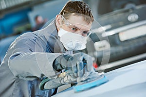 Auto repairman grinding autobody bonnet