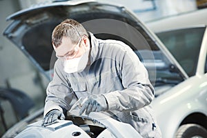 Auto repairman grinding autobody bonnet