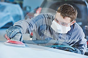 Auto repairman grinding autobody bonnet