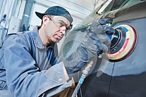 Auto repairman grinding autobody bonnet