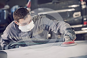 Auto repairman grinding autobody bonnet