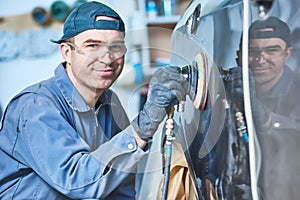 Auto repairman grinding autobody bonnet photo