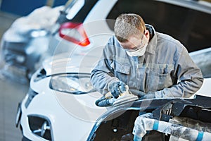 Auto repairman grinding autobody bonnet photo