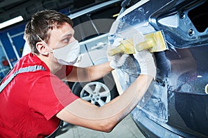 Auto repairman grinding automobile body