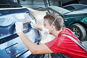 Auto repairman grinding automobile body
