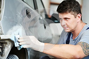 Auto repairman plastering autobody bonnet