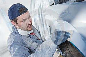 Auto repairman plastering autobody bonnet