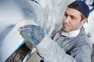 Auto repairman plastering autobody bonnet photo