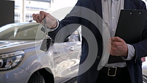 Auto sale center, professional car seller guy holds in hands keys to new automobile for sale in dealership