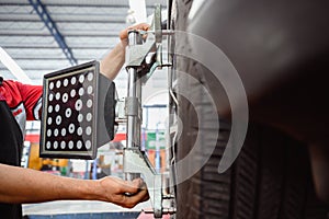 Auto service mechanic installing wheel alignment sensor on tire during vehicle suspension alignment adjustment. and set the car