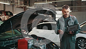 Auto service, repair, maintenance concept. mechanic checks the car, making diagnostics with laptop at the service