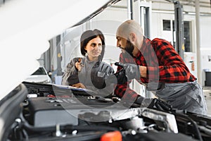 Auto service, repair, maintenance and people concept - mechanic men with wrench repairing car engine at workshop