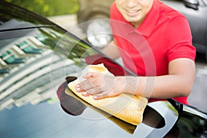 Auto service staff cleaning car rear windshield with microfiber