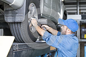Auto services and Small business concepts. The car service mechanic is replacing the wheels. Removing the wheel
